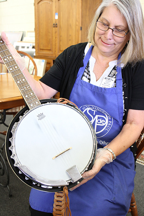 Josie inspects a banjo for resale online at the Mesa Thrift Store.