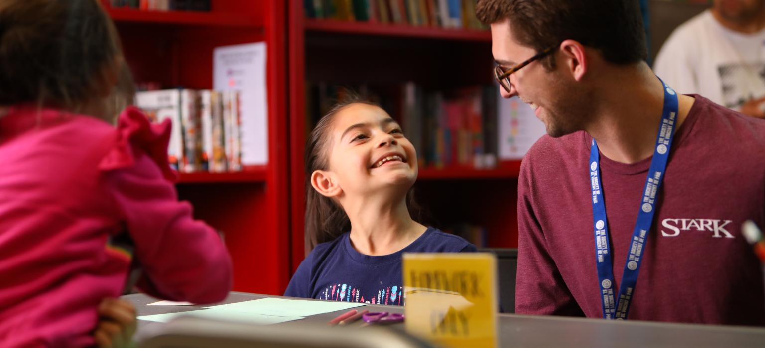 Youth Education Header young girl looking up at teenage boy while working on homework
