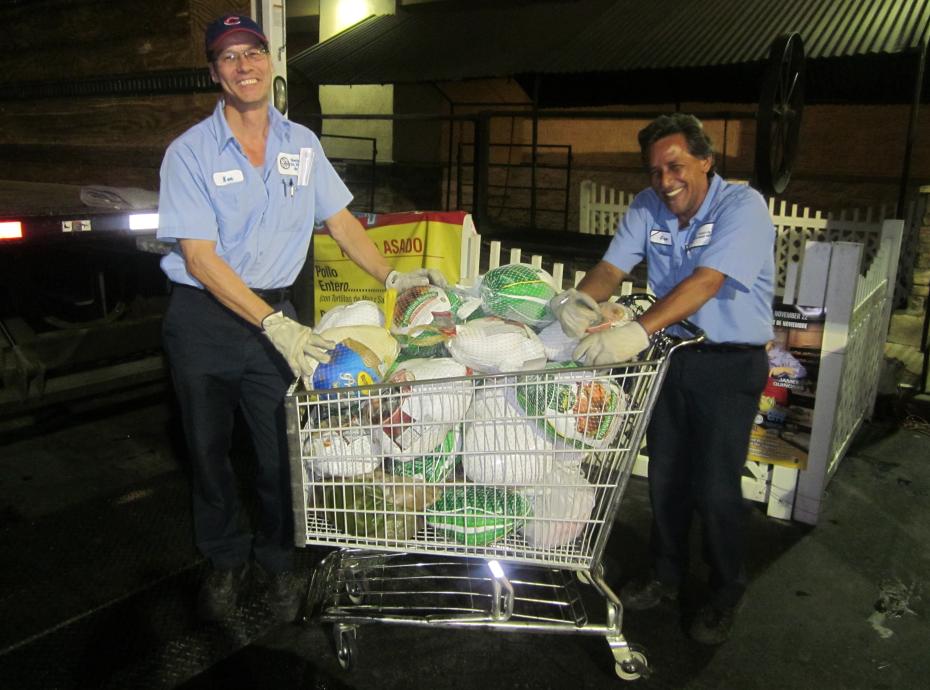 Two men with a cart of turkeys on the back of a truck