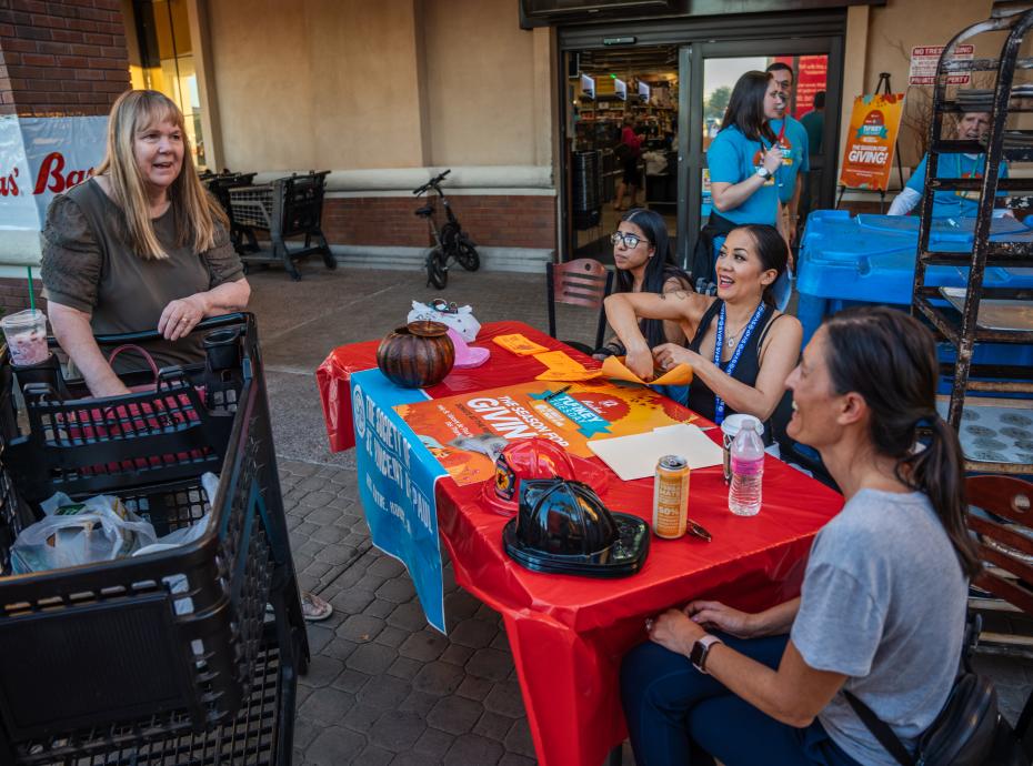 Woman pushing a cart and talking to volunteers on Turkey Tuesday