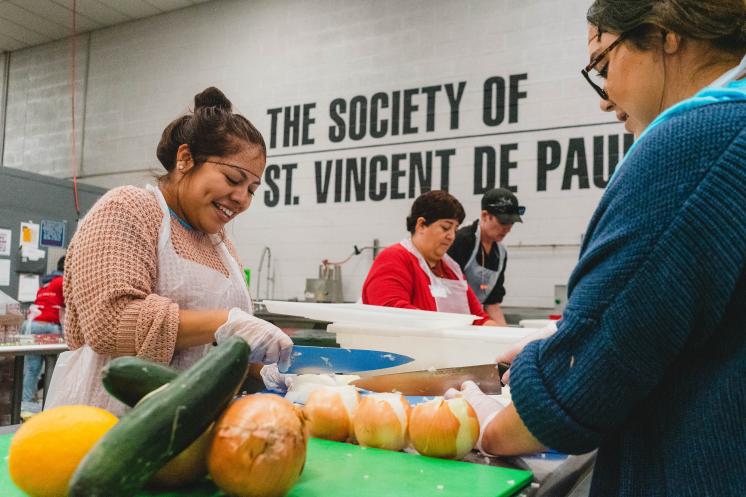 Two women smiling and chopping vegetables