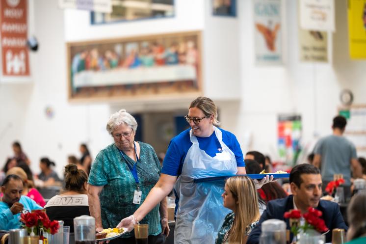 Volunteer serving dinner in family dining room