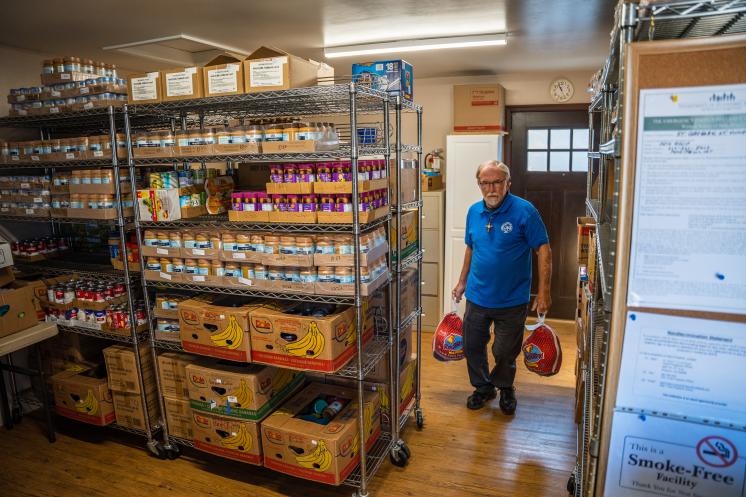 Older man holding two turkeys in a food pantry