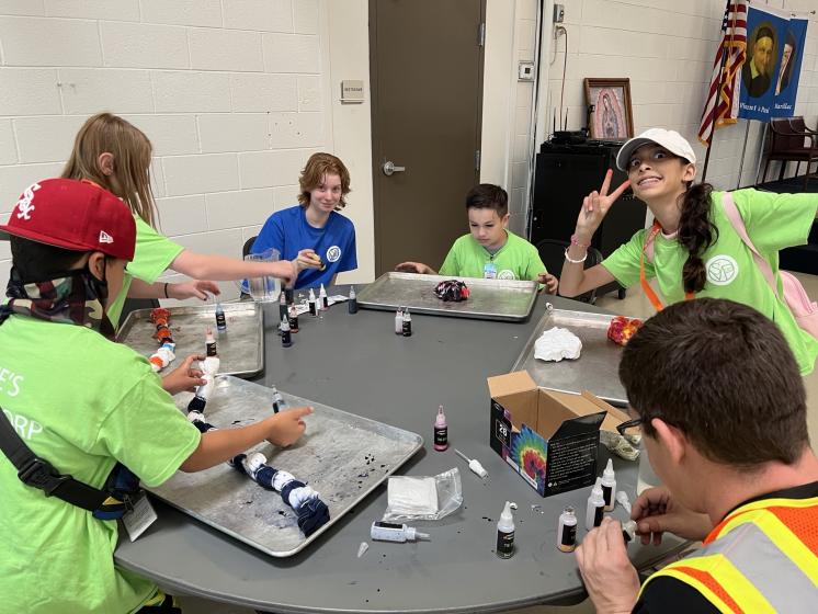 Kids tie dying shirts around a table