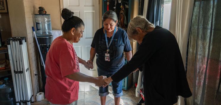 Vincentians pray with a food box recipient in her home.