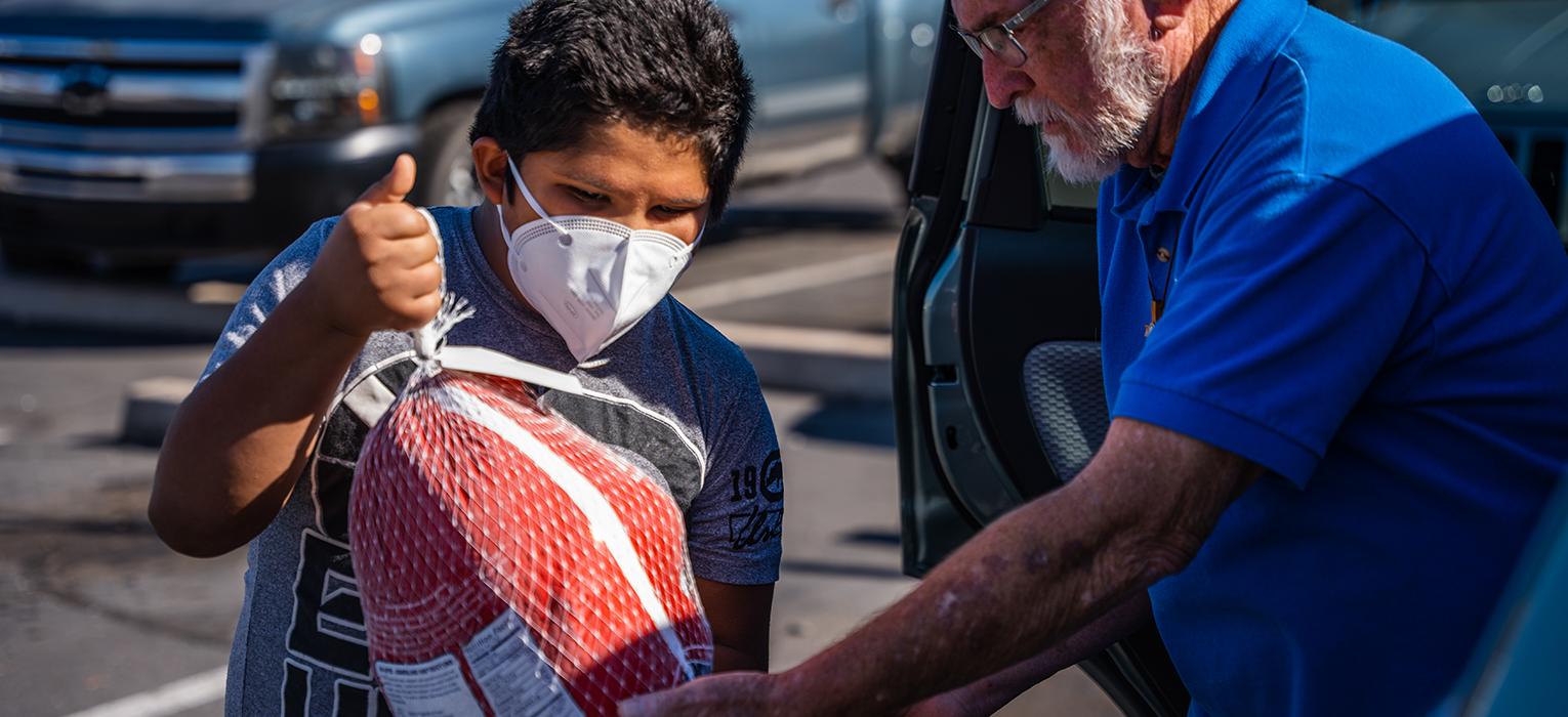 A Vincentian hands a turkey to the boy of a family in need this Thanksgiving