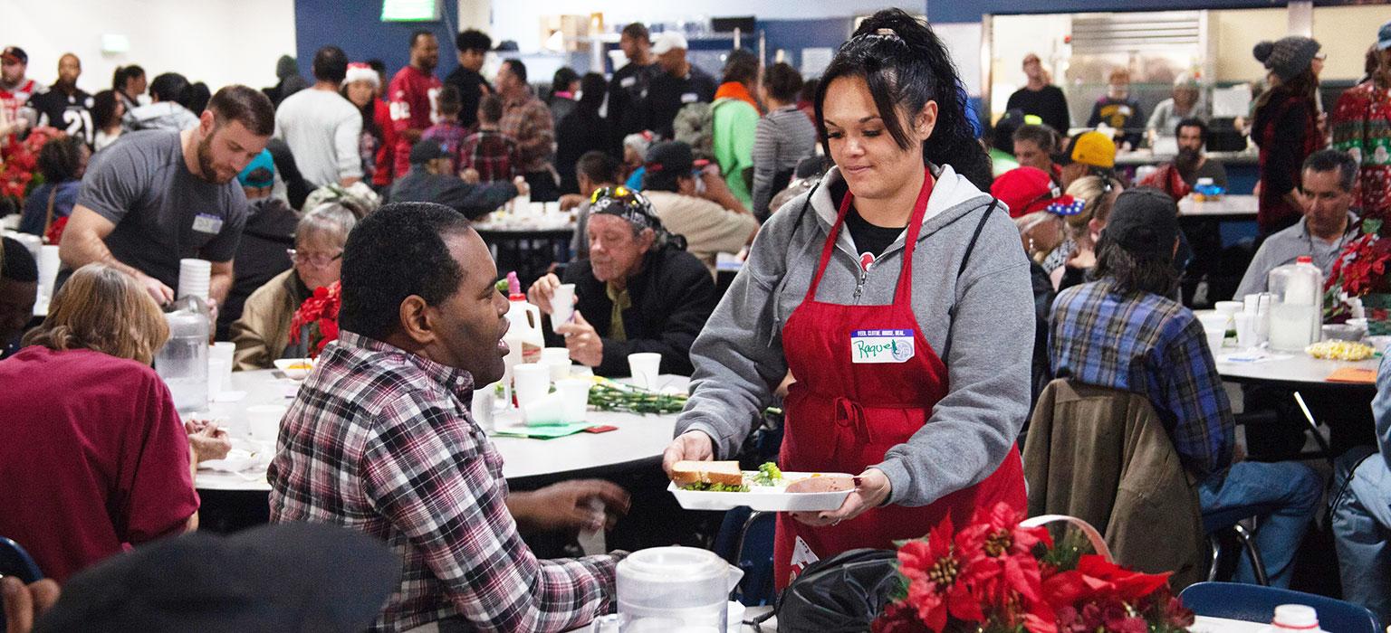 A volunteer serves a guest a meal on Christmas Day at SVdP's Phoenix Dining Room