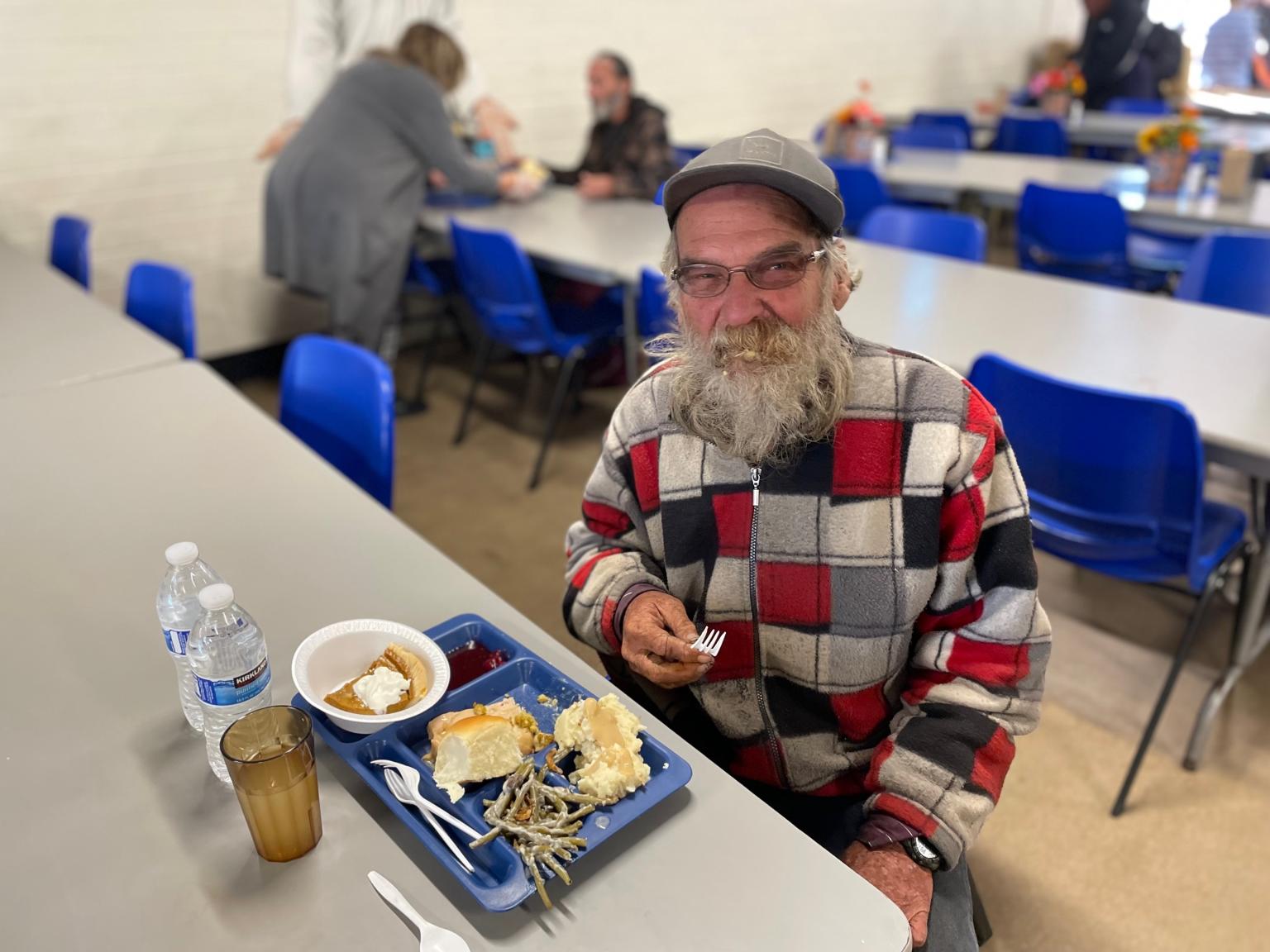 Man eating a thanksgiving meal in the dining room looking up at the camera