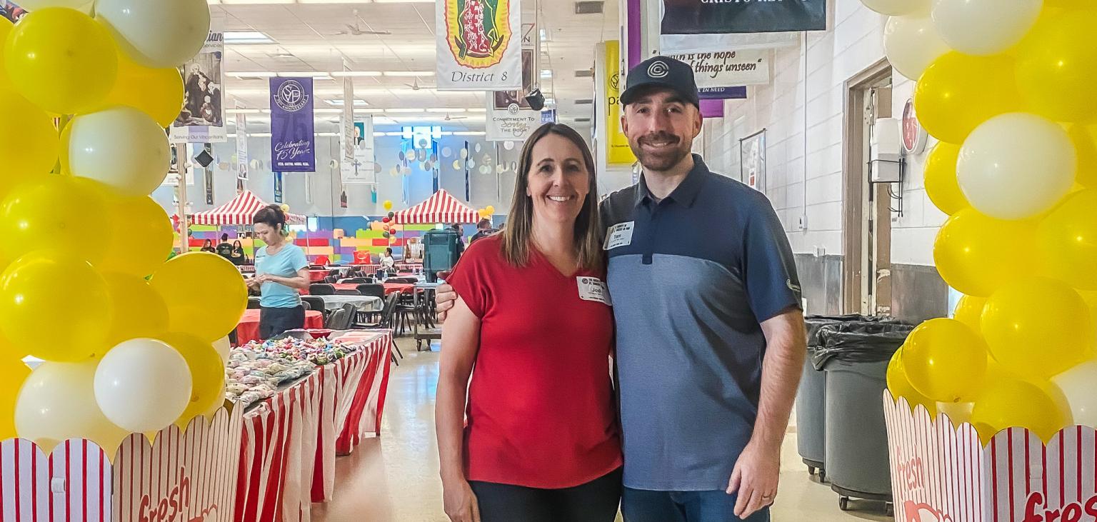 Tom and Jodi Chermack stand at the carnival they organized and sponsored at SVdP's Hall of Banners.