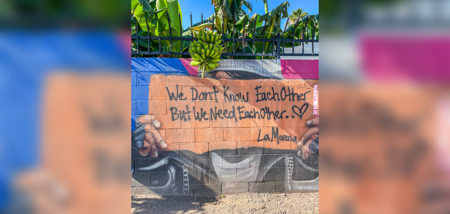 A banana tree outside SVdP's Mesa Dining Room points to an important message written on a mural that says, "We don't know each other, but we need each other..."