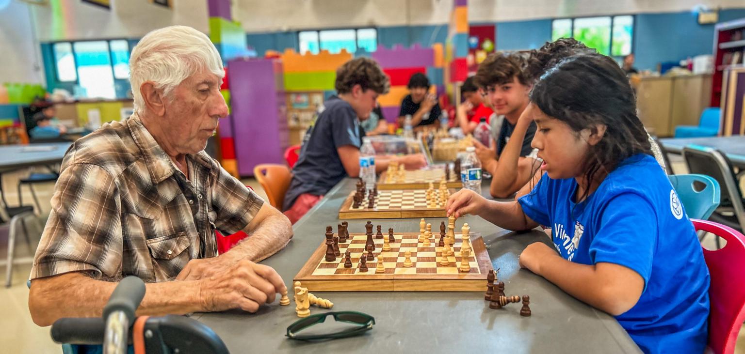 Older Ozanam Manor resident Tobias plays chess with the young Dream Center student Victoria.