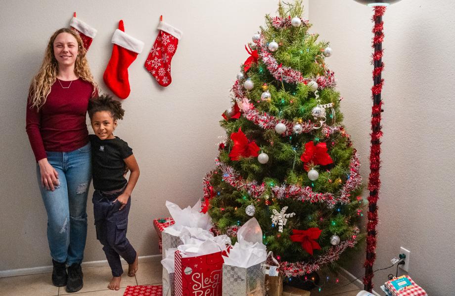 Christin and Keira stand next to their tree with new presents under.