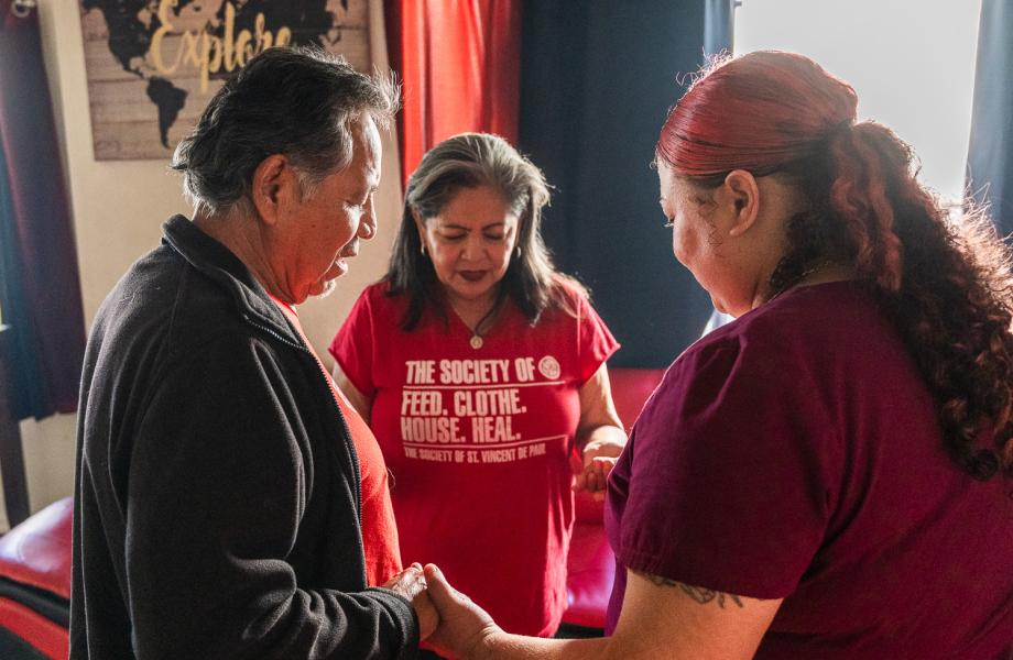 Vincentians pray with a mother during a home visit.