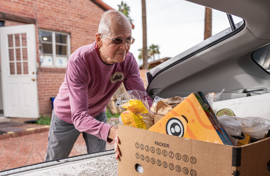 A Vincentian volunteer puts a box of food in their car for delivery to a family in need.