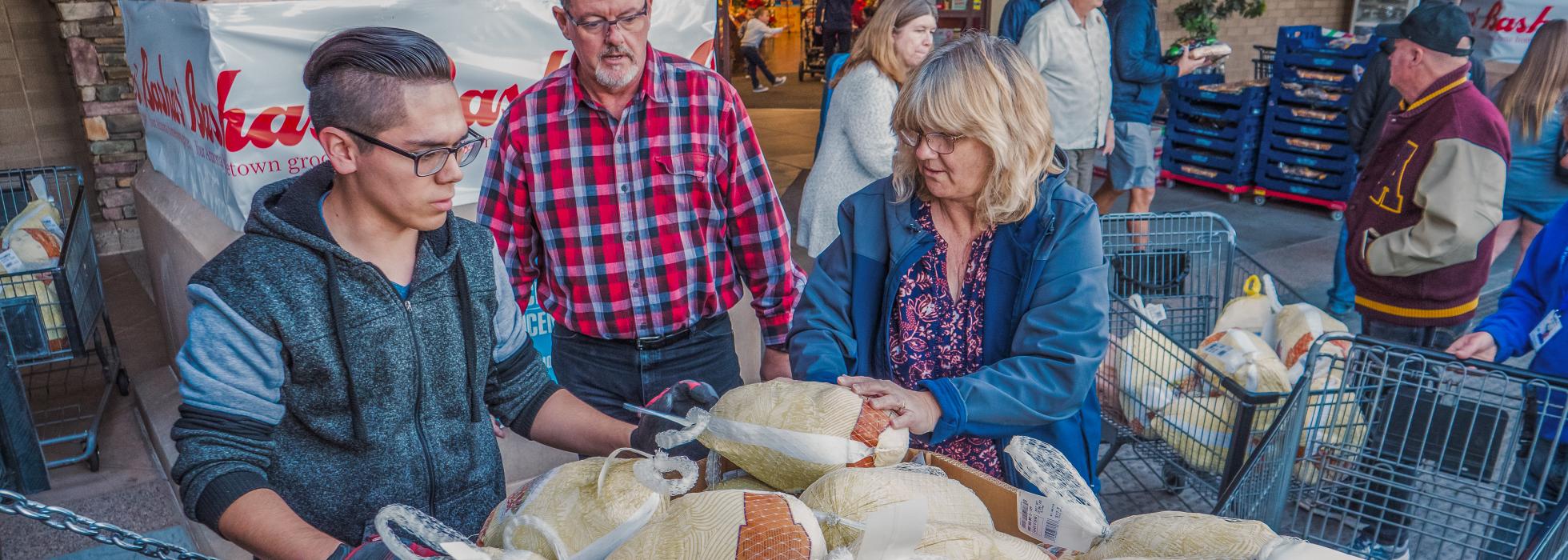 A volunteer helps a donor with their donated turkey.