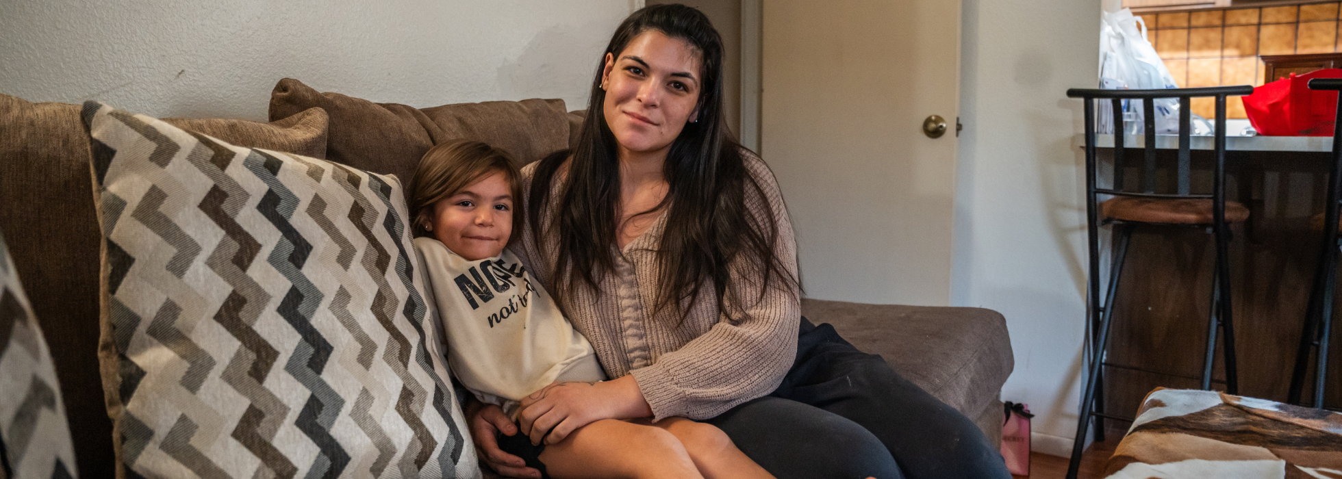 A mom and her young daughter sitting on the couch