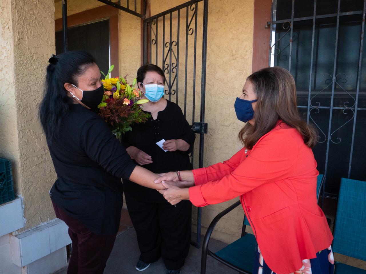 Women greeting each other outside of a house