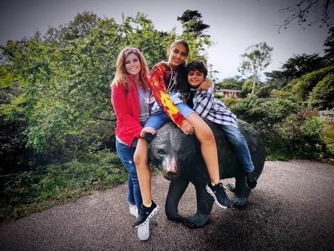 Woman and two kids sitting on a bear statue