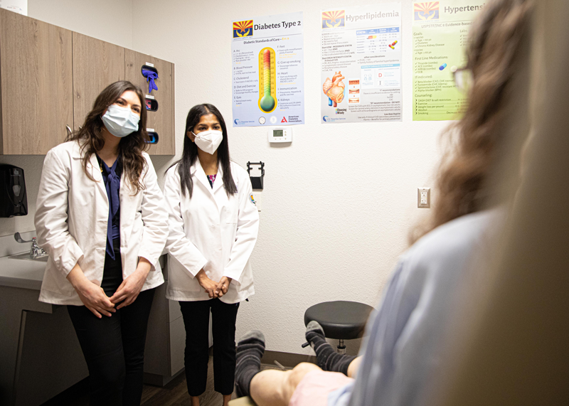 Two women standing in a patient's room listening