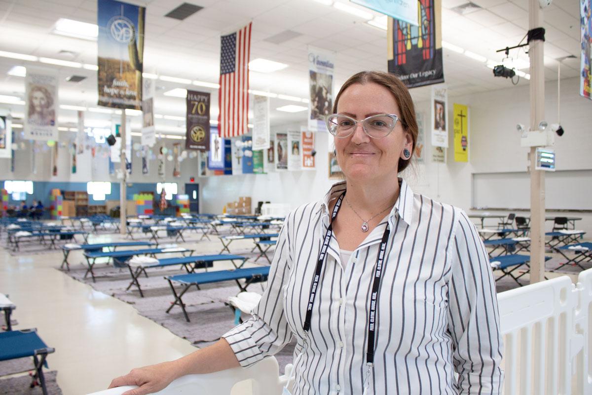 Woman smiling at the camera in a room full of cots