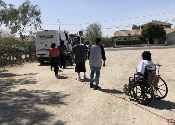 Line of people waiting to get cold water bottles from a van