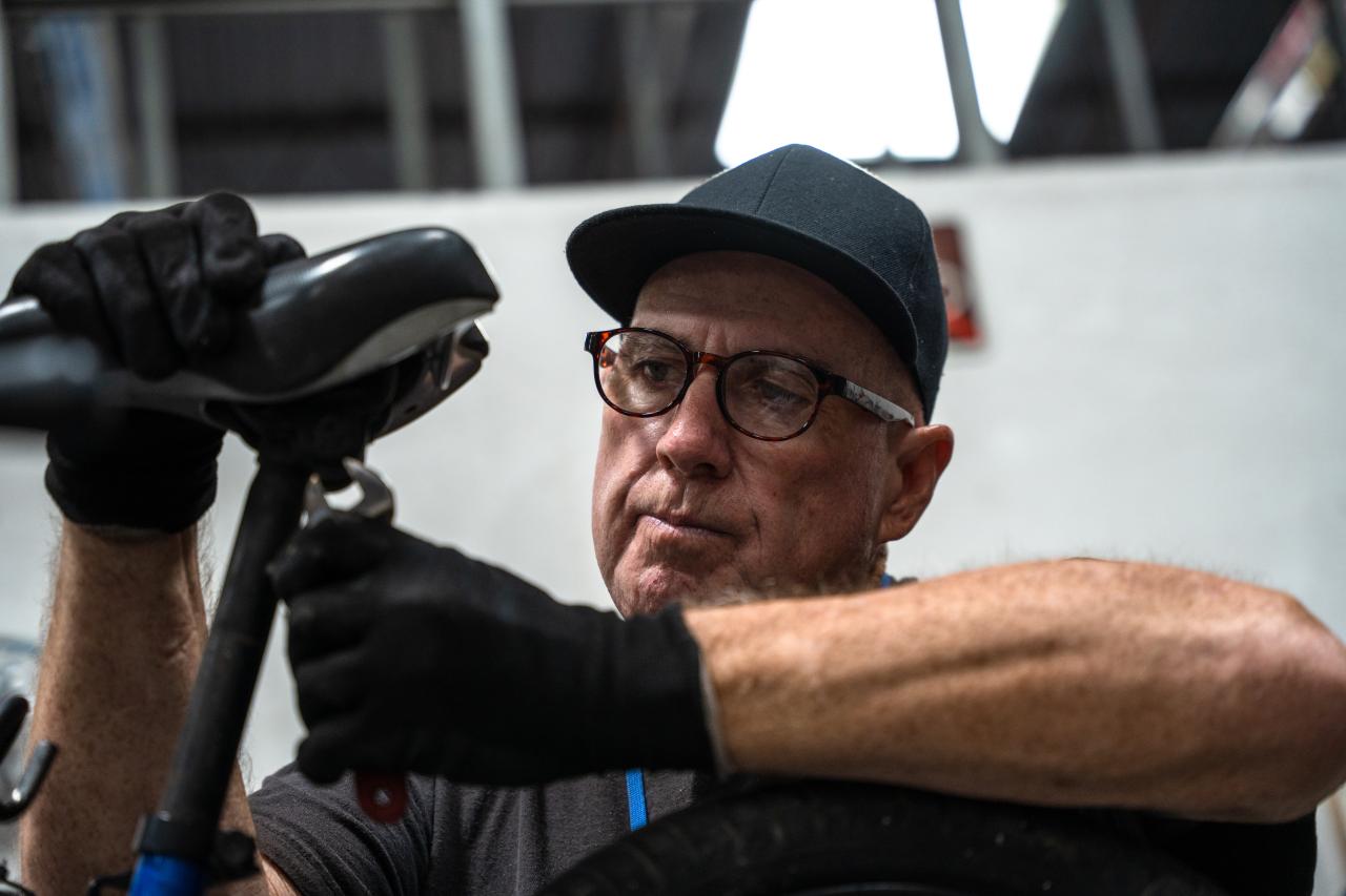 Ricky tightens a screw on a bike he's fixing