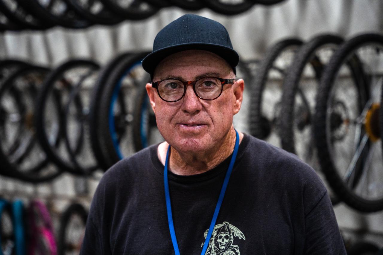 Ricky poses for his portrait in front of a background of bike tires.