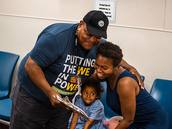 Man putting his arm around a woman and child in the resource center