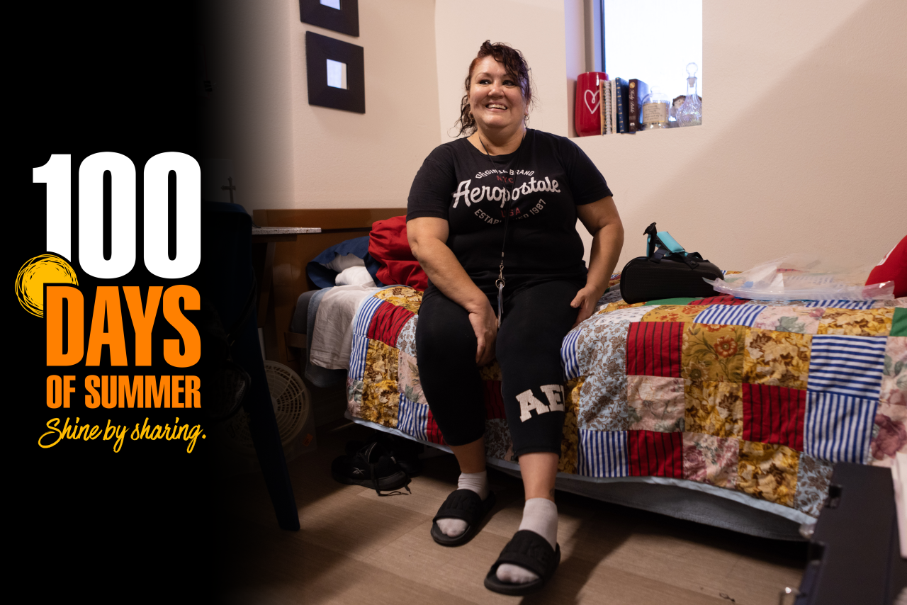 Woman sitting on bed at SVdP shelter with 100 Days of Summer logo