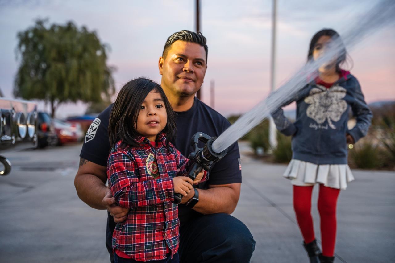 One of Nashelly's sons fires off the water hose with the help of a firefighter.