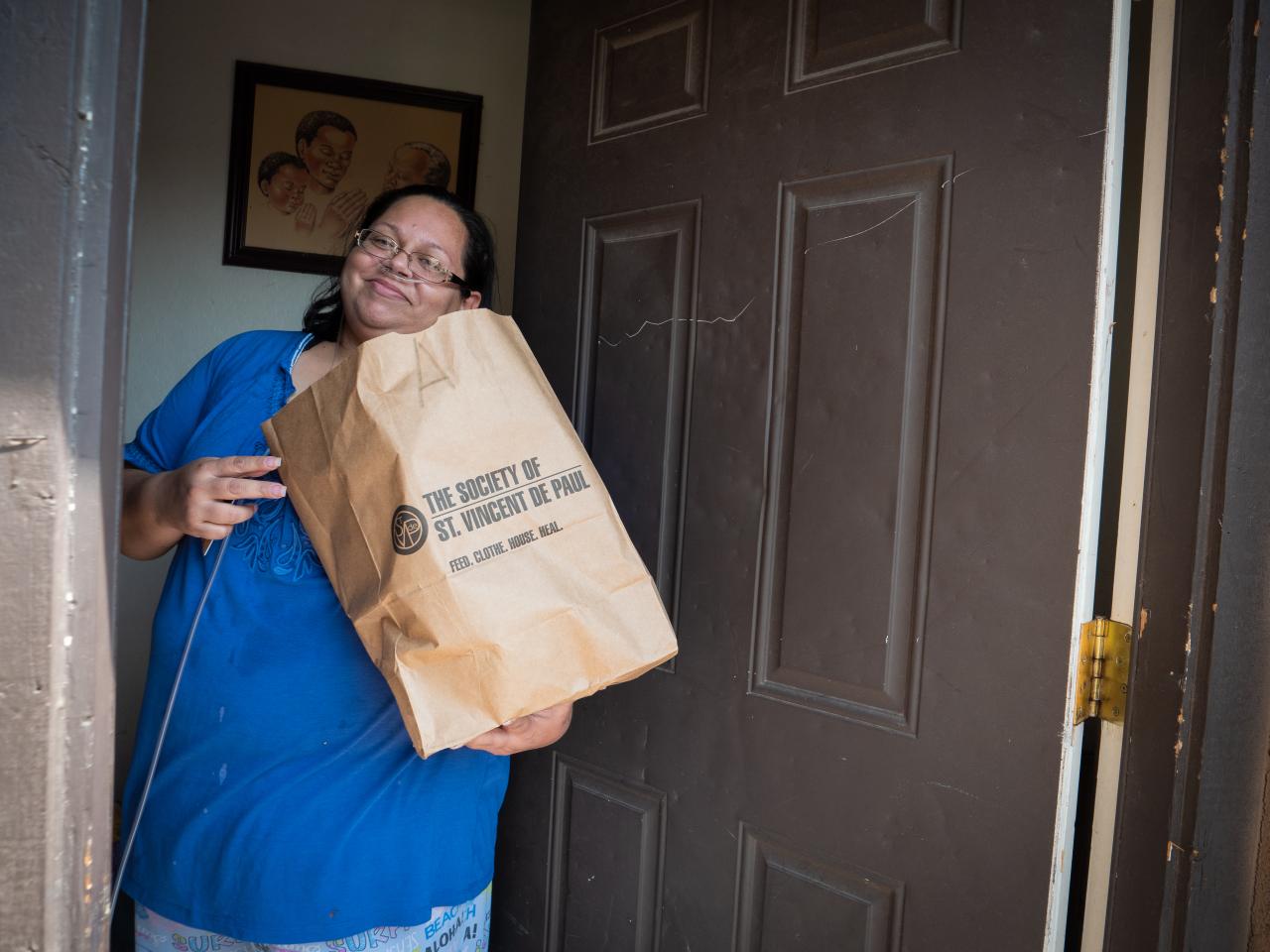 woman holding a food box standing in the doorway of her apartment