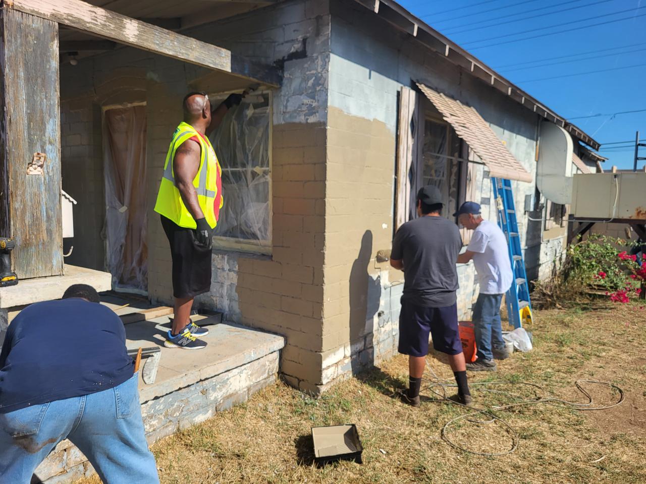 Members of the Neighborhood Brigade repaint John Harper's house.