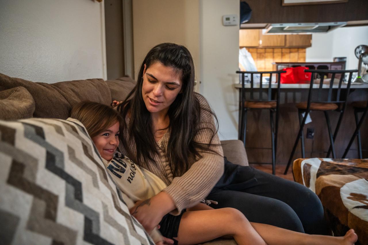 Jesse and her daughter sit on their couch in their apartment.