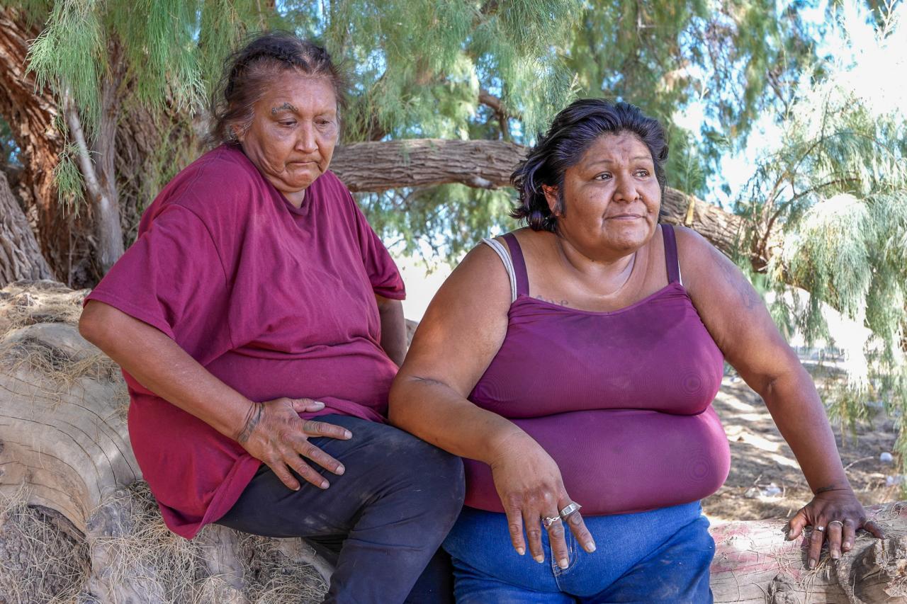 Rae Valdez and Tillma Sanchez sit under a tree near their encampment.