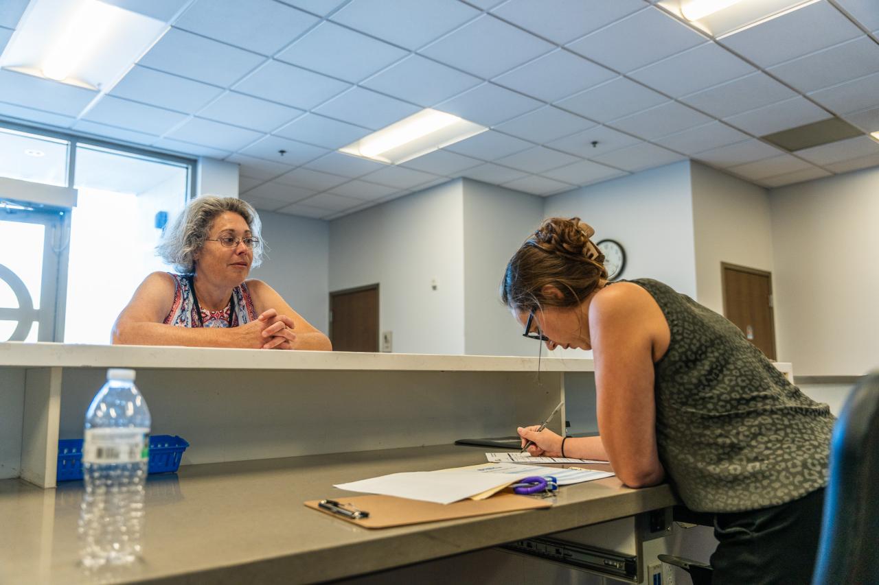 Carmela waits as Lindsay fills out paperwork for Carmela's bed.