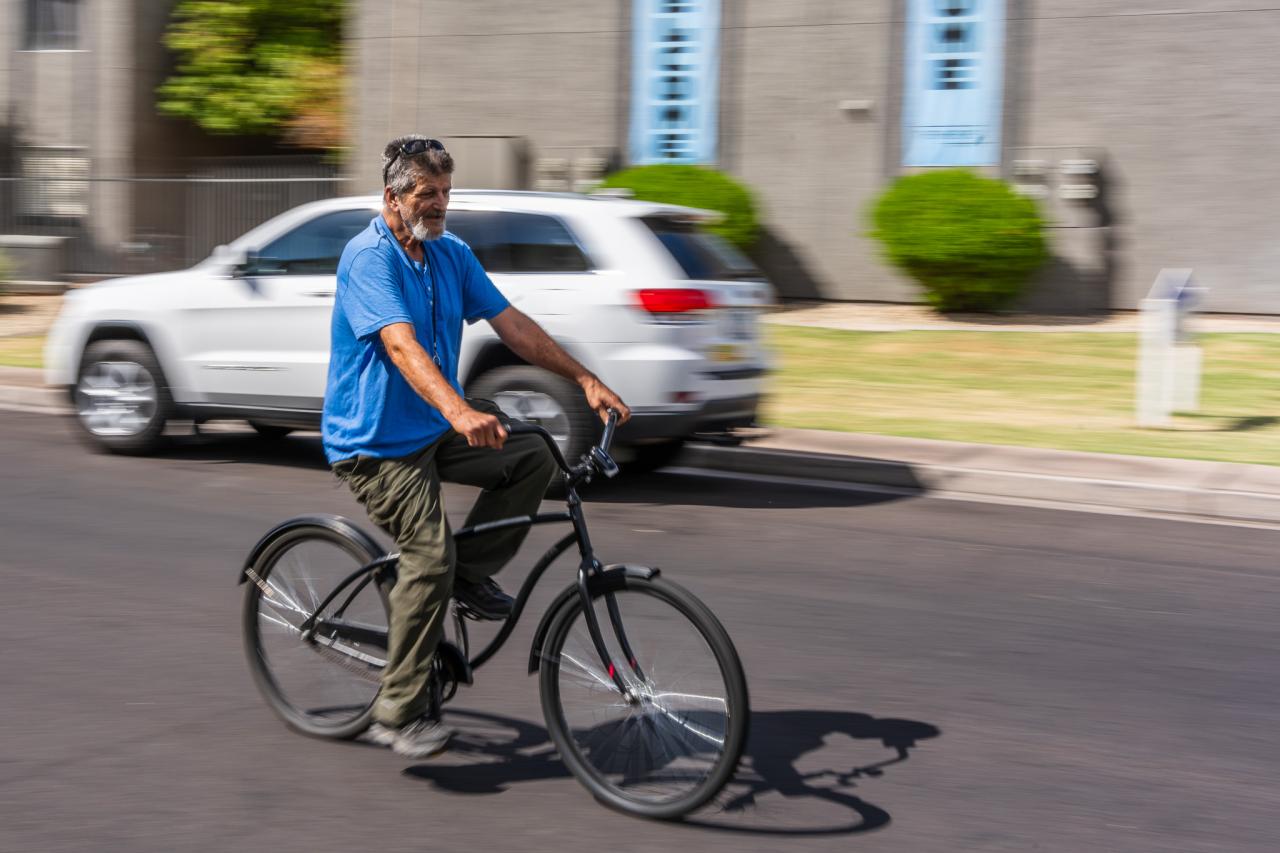 Kenneth rides his bike down a street.