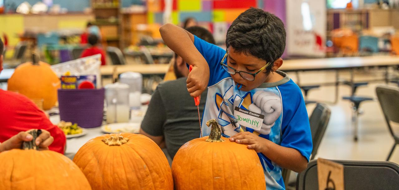 A young guest at Family Evening Meal focuses on carving his pumpkin.