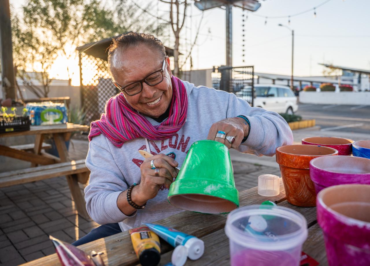 Patricio paints one of the pots he brought at the Rob and Melani Walton Urban Farm.