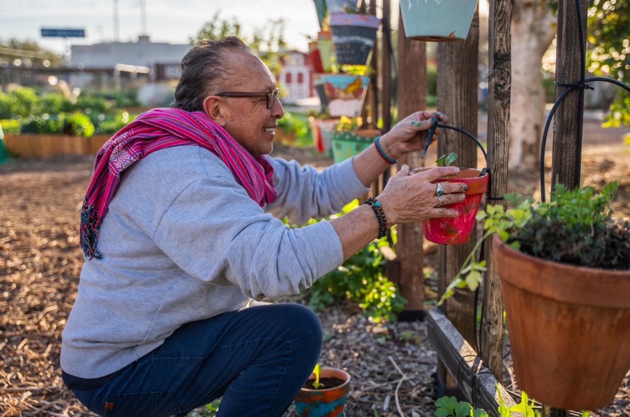 Patricio hangs up the finished potted plant at a trellis in SVdP's Rob and Melani Walton Urban Farm.