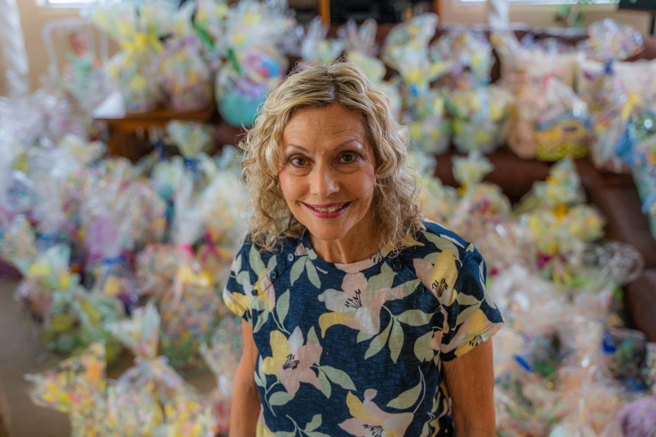 Debi stands in front of the dozens of Easter baskets.