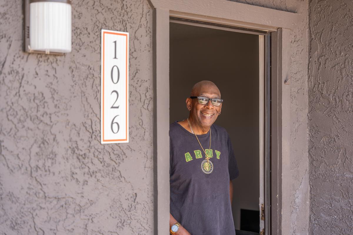 John smiles in the doorway of his new apartment.