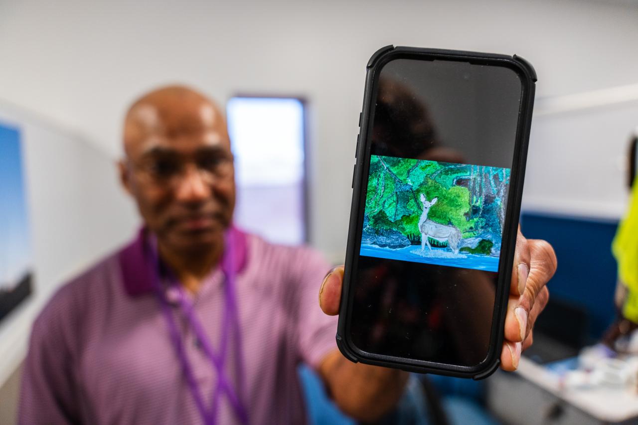 Derek holds up a photo of his painting.