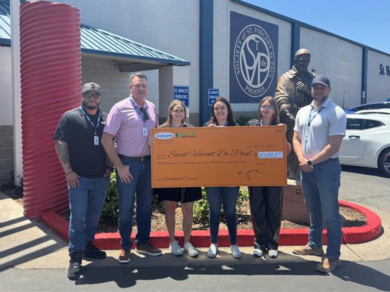 Representatives from Sunland Asphalt and Construction deliver a check to SVdP's main campus.