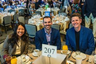 Three people sitting at a table at the Restoring Hope Community Breakfast