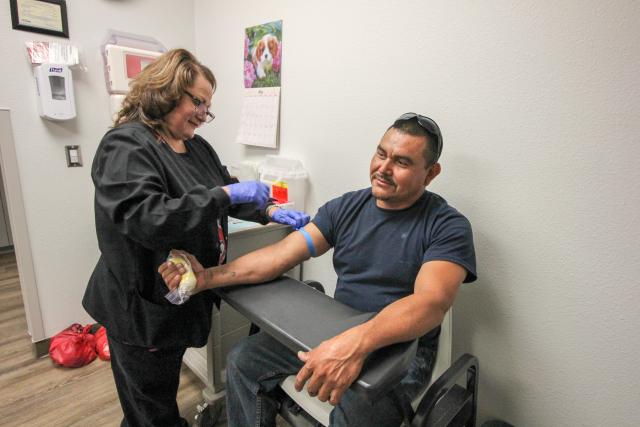 Female doctor drawing the blood of a male patient