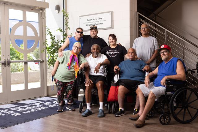 A group of shelter residents pose together in the lobby of Ozanam Manor