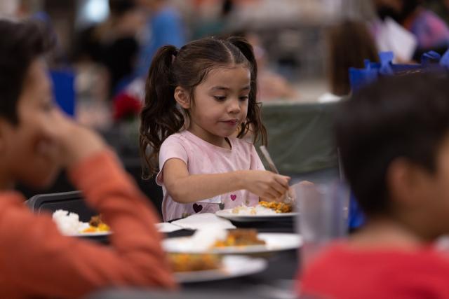 young girl eating a plate of food