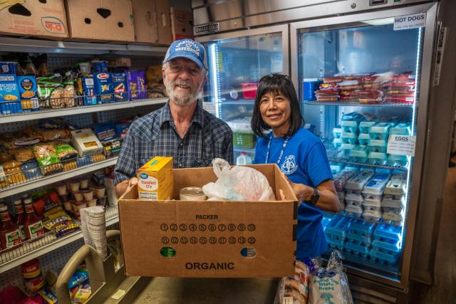 two volunteers holding a food box in a food pantry