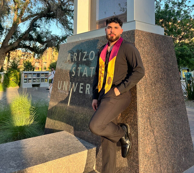 Russvel poses for graduation pictures after he completed his degree from ASU.